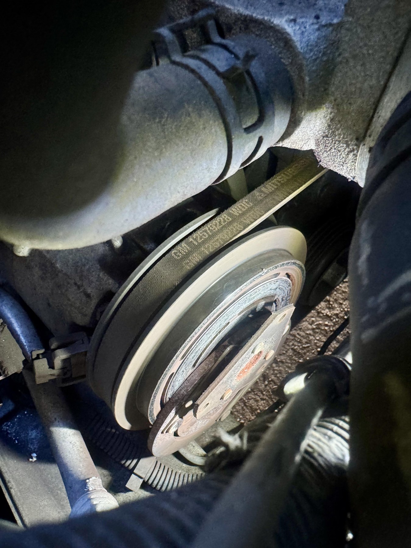 Corvette compressor clutch viewed in place, with the clutch face displaced beside the pulley.